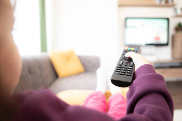 Child watching cartoon on TV remote control in hand